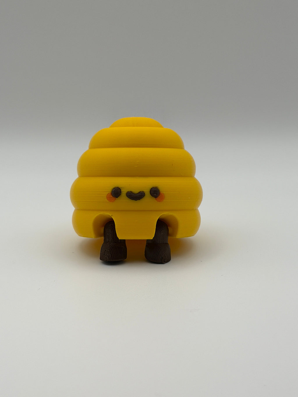 Yellow beehive fidget clicker with a keyring attachment, a brown smiley face, and brown articulated legs. 