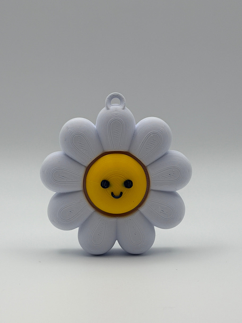 White flower-shaped object with a yellow center and smiley face on a gray background