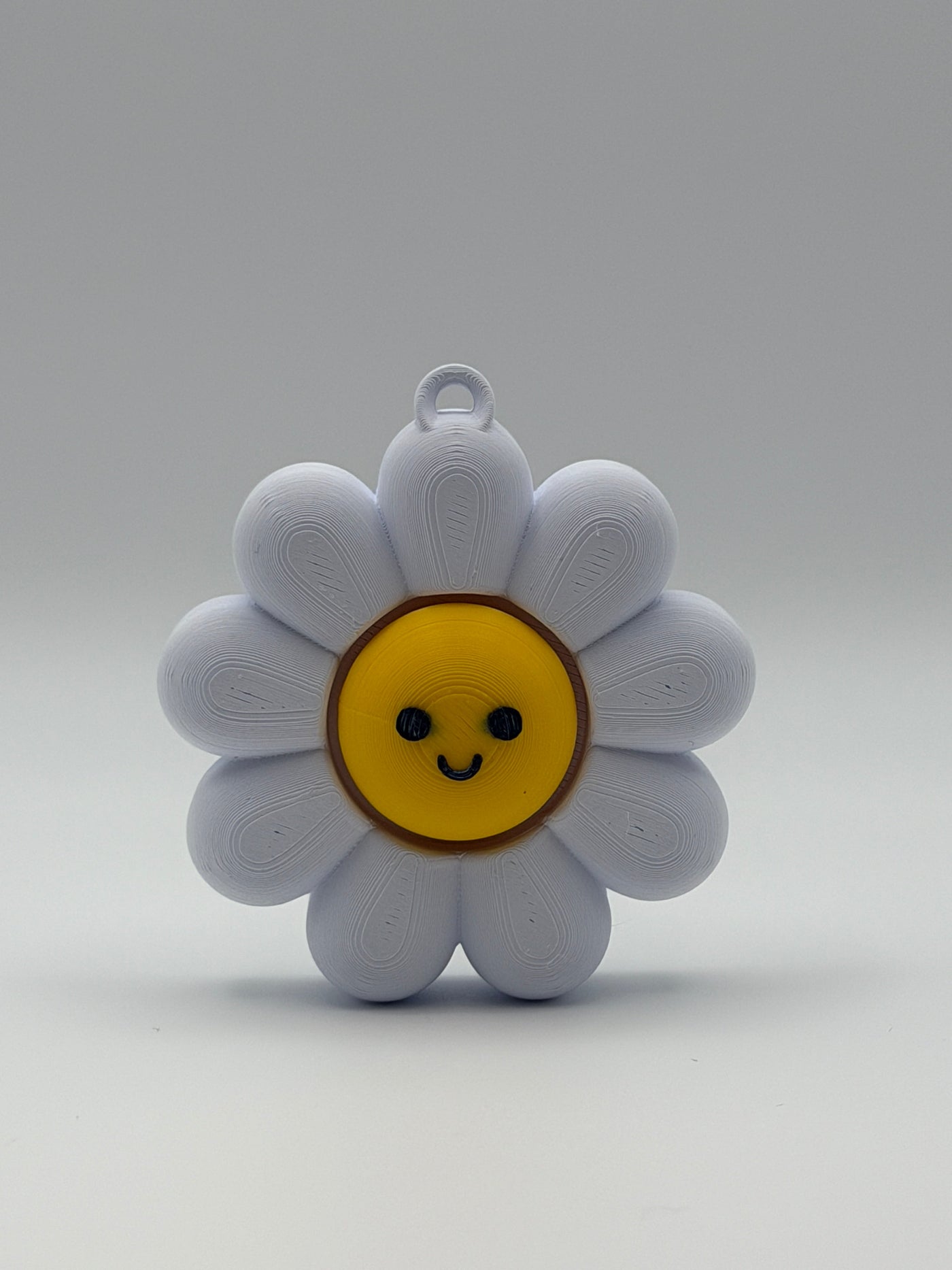 White flower-shaped object with a yellow center and smiley face on a gray background