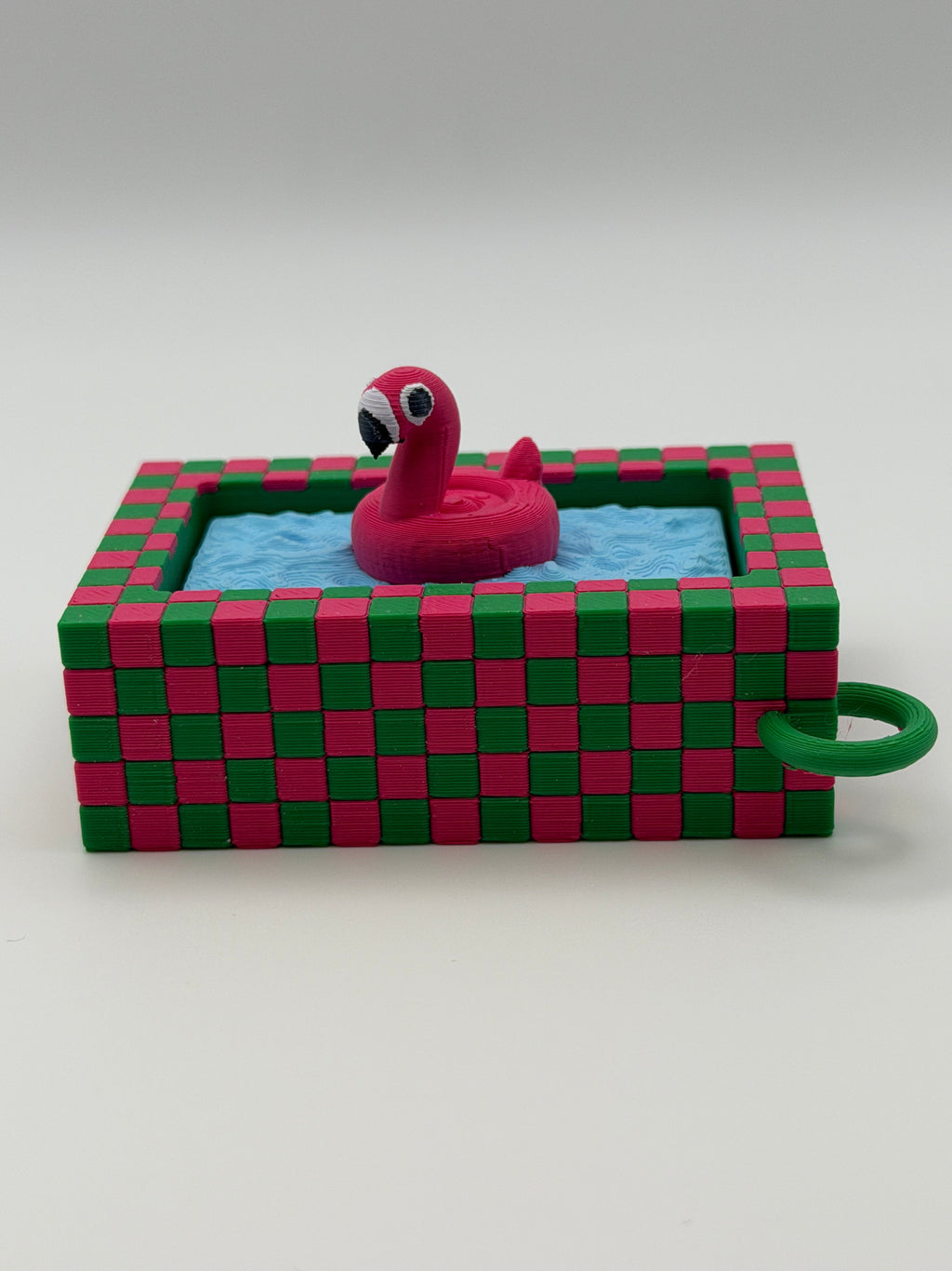 A pink flamingo in a blue pool fidget clickers with a green keychain and textured pink and green external base.