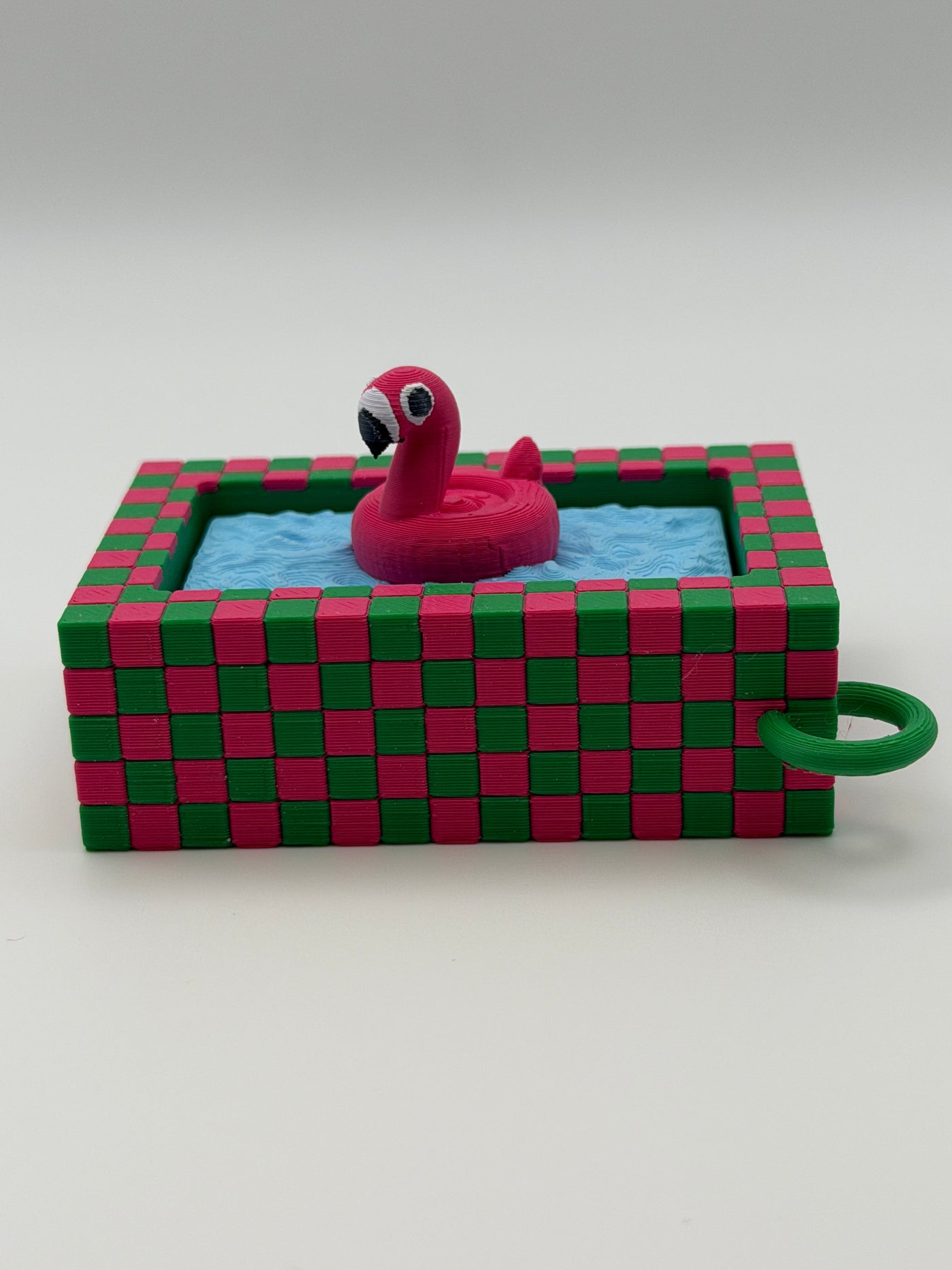 A pink flamingo in a blue pool fidget clickers with a green keychain and textured pink and green external base.