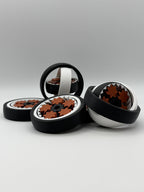 Four gyro spinning fidget toys. A black exterior layer, followed by a white layer, followed by another black layer that spins. 5 bronze coloured star shape wheels wrapped around a black star shape cog that spins the bronze wheels. 
