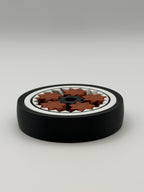 A gyro spinning fidget toy. With a black exterior layer, followed by a white layer, followed by another black layer that spins. 5 bronze coloured star shape wheels wrapped around a black star shape cog that spins the bronze wheels. 