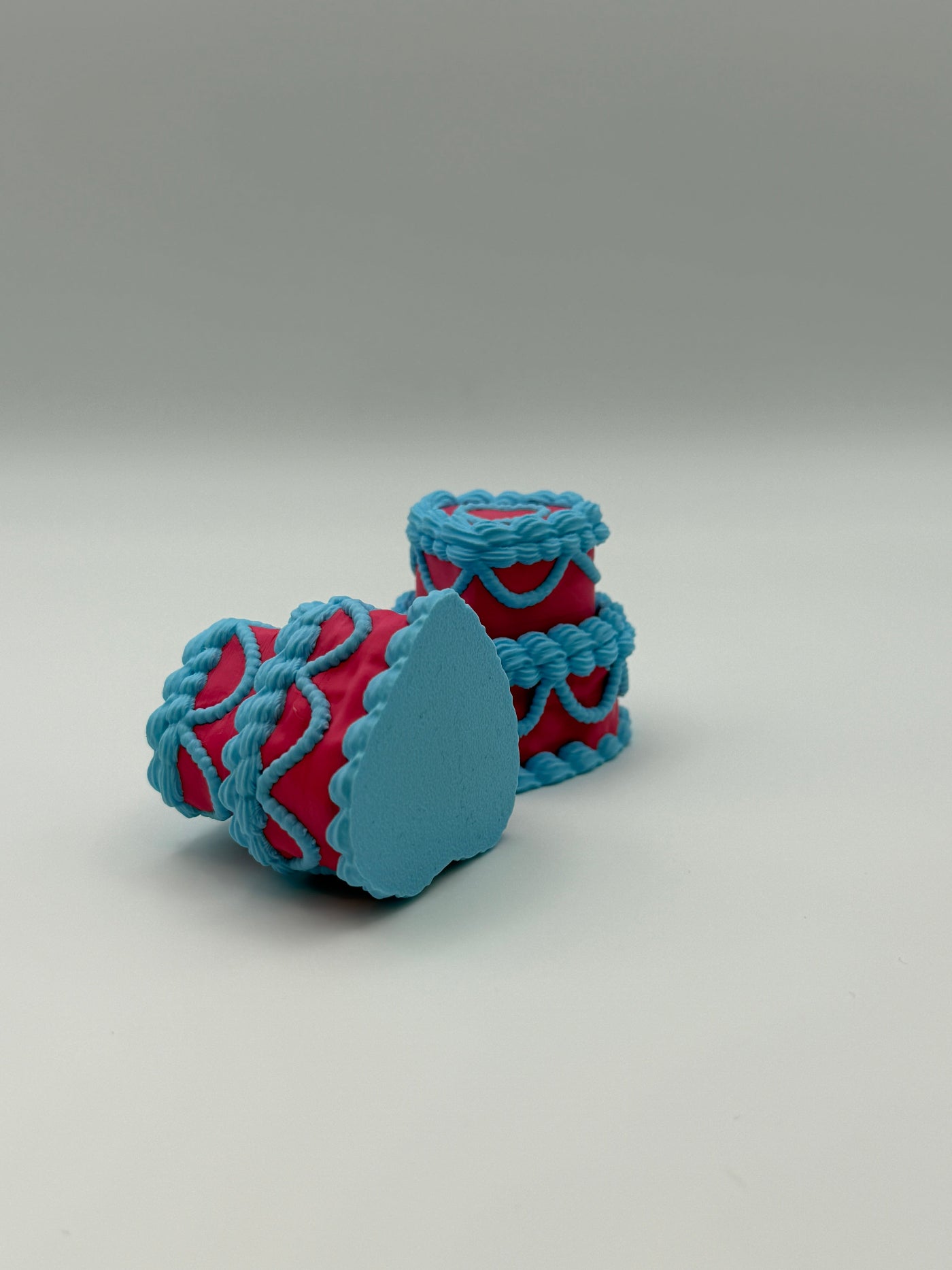 Two pink and blue layered cake fidget clickers.
