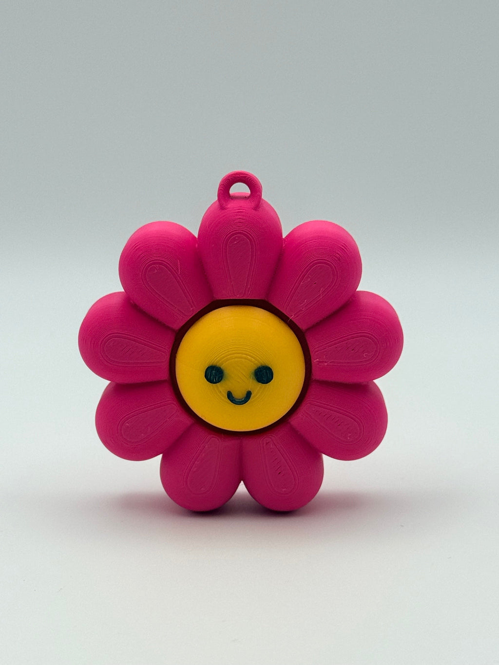 Pink flower-shaped object with a black smiley face and yellow center on a white background