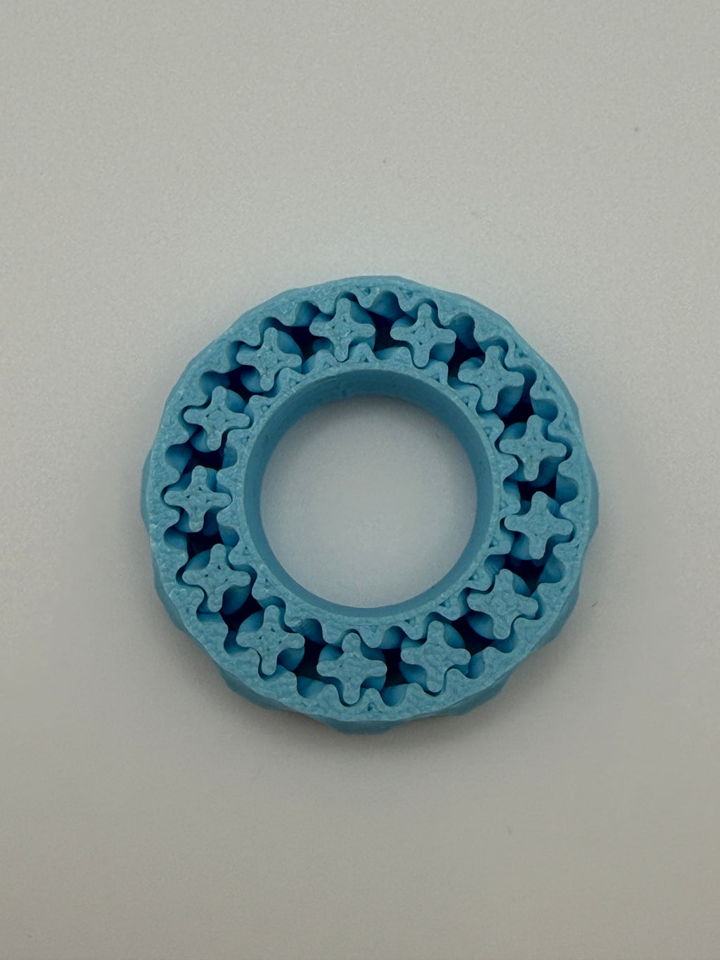 Blue plastic ring with star-shaped cutouts on a gray background