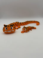 Two large and small articulated orange tigers with black stripes and grinning teeth.  The small one has a keychain attachment. 