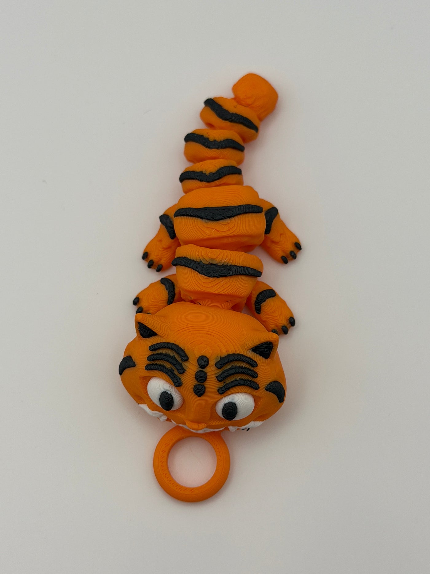 Small orange tiger with black stripes and grinning teeth with a keychain attachment. 