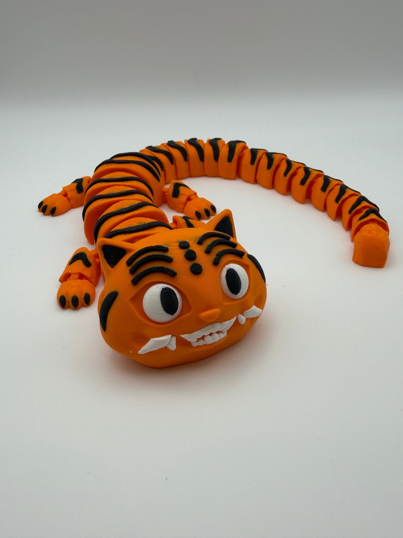An orange and black striped tiger articulated toy with grinning teeth.