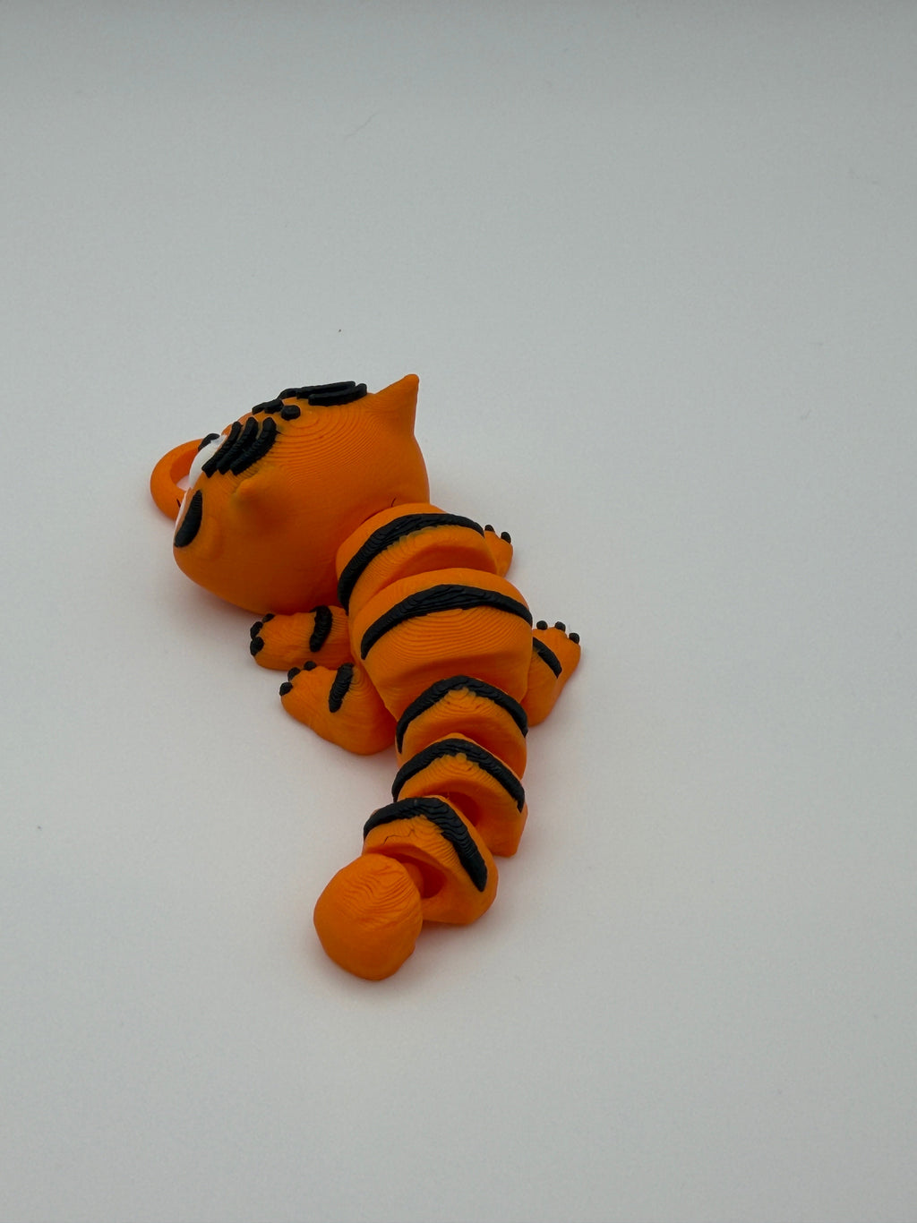 Small orange and black striped tiger articulated toys with grinning teeth with a keychain attachment. 