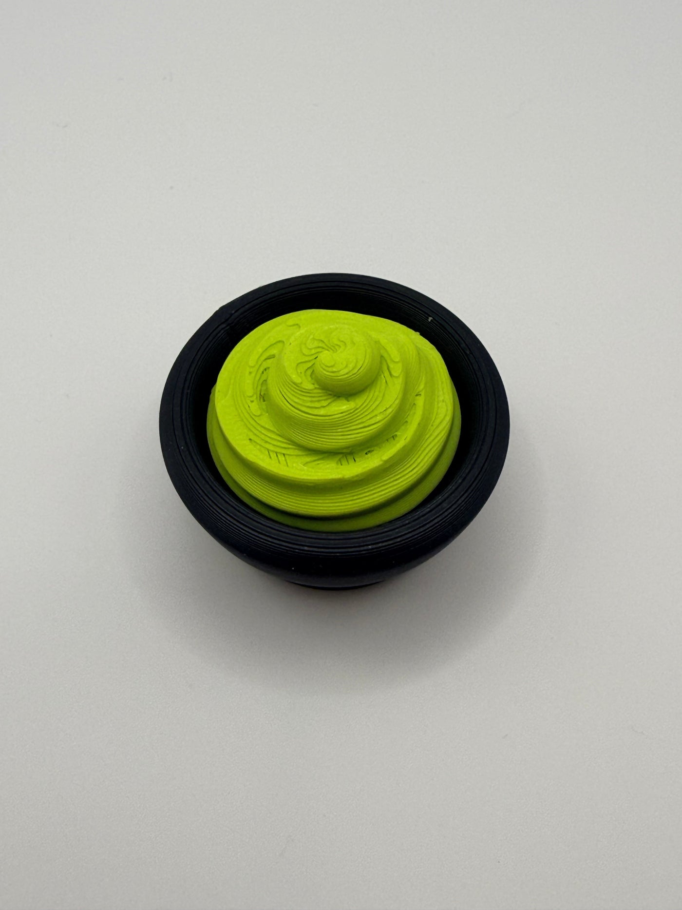 Green wasabi fidget clicker in a black bowl.