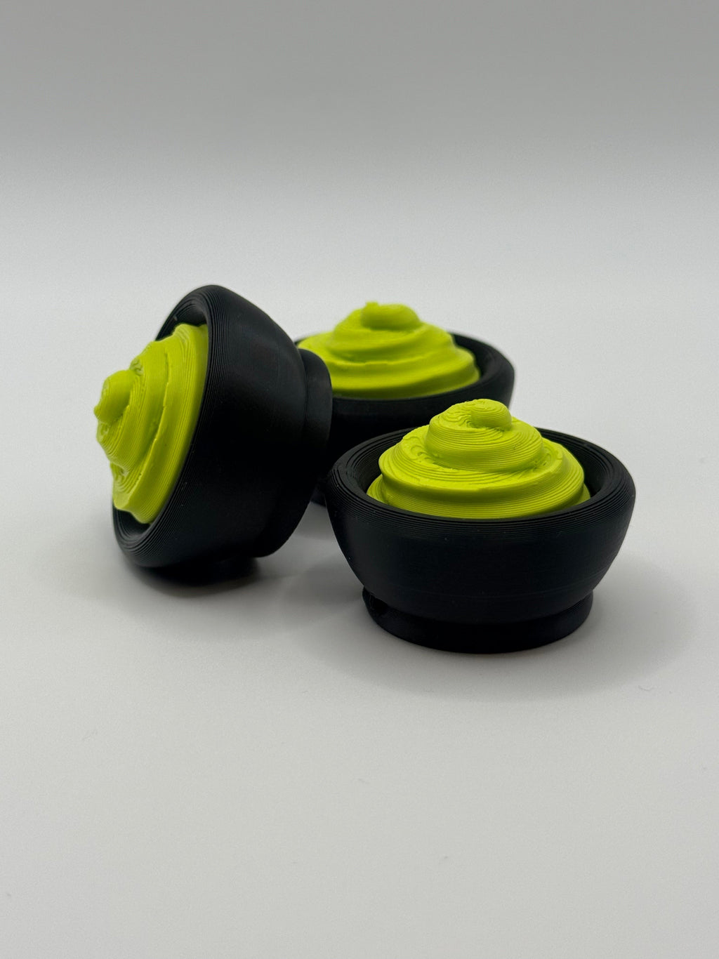 3 Green wasabi fidget clickers in a black bowl.
