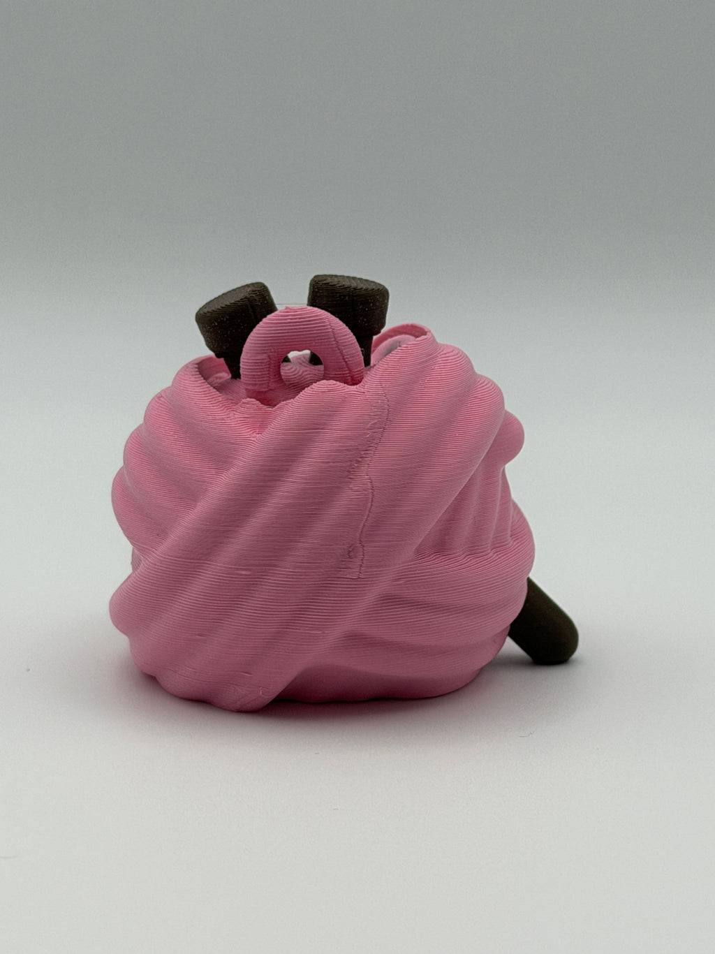 A pink articulated yarn ball fidget clicker with brown feet, one brown hand, and two brown needles in the head.