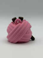 A pink articulated yarn ball fidget clicker with brown feet, one brown hand, and two brown needles in the head.