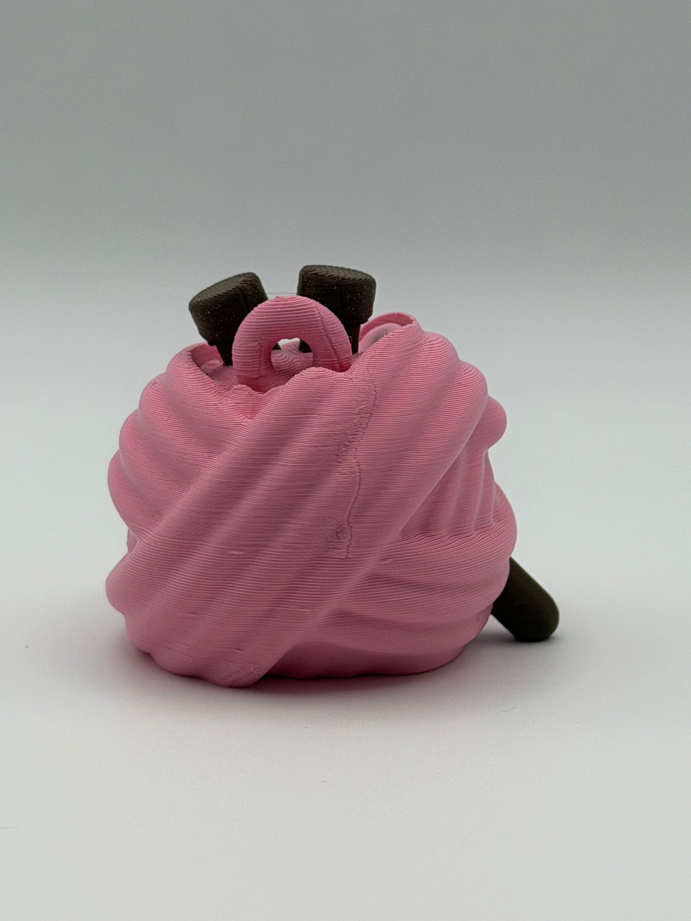 A pink articulated yarn ball fidget clicker with brown feet, one brown hand, and two brown needles in the head.