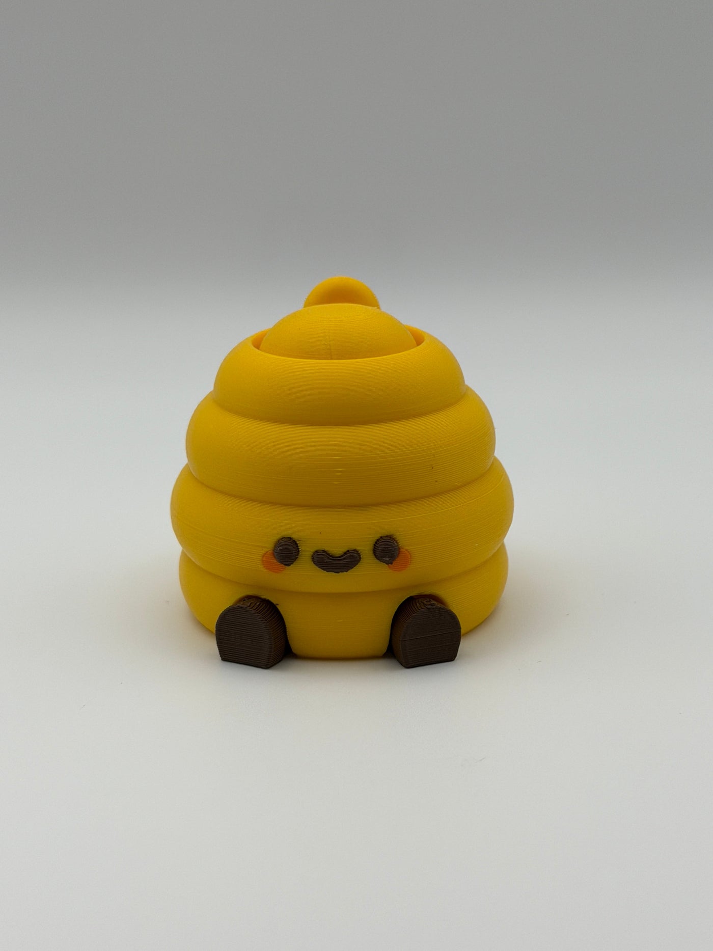 Yellow beehive fidget clicker with a keyring attachment, a brown smiley face, and brown articulated legs. 