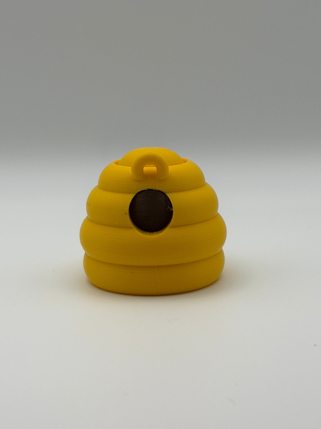 Yellow beehive fidget clicker with a keyring attachment, a brown smiley face, and brown articulated legs. 