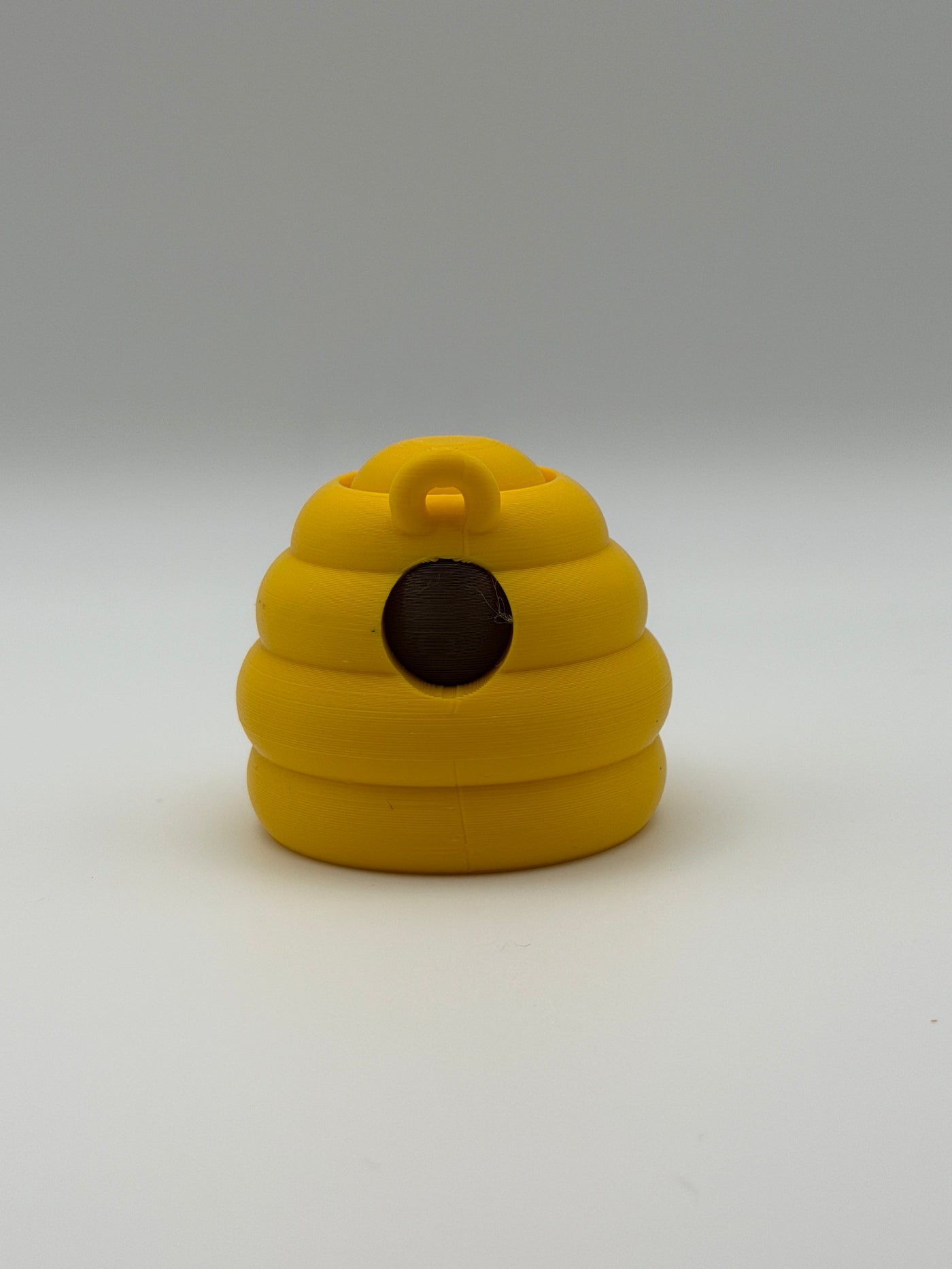 Yellow beehive fidget clicker with a keyring attachment, a brown smiley face, and brown articulated legs. 
