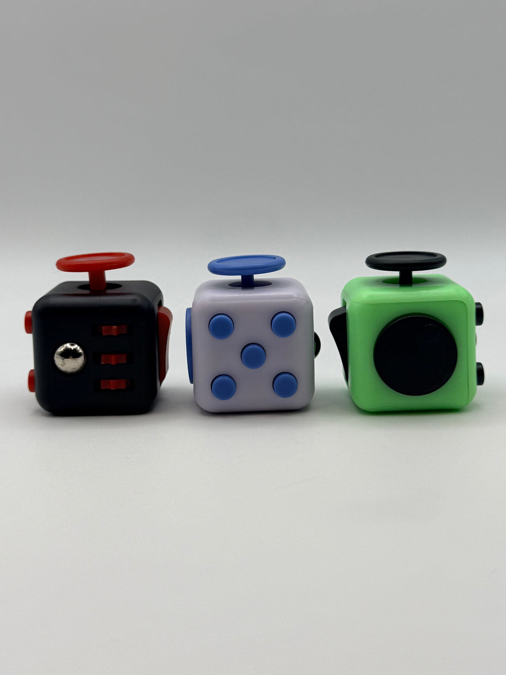 Three fidget cubes in different colors on a white background