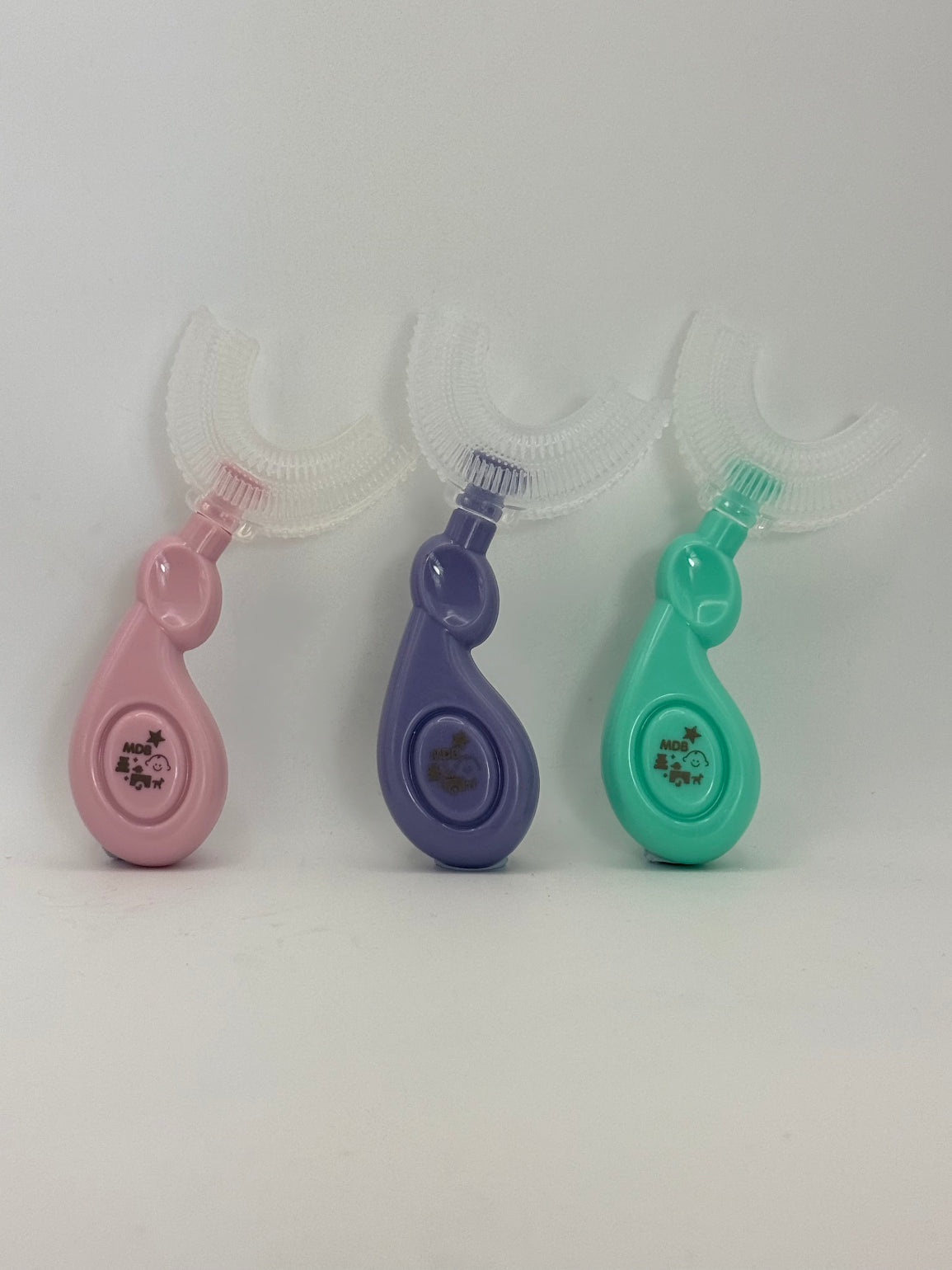 3 U-shaped sensory toothbrushes. Green, purple and pink on a white background.