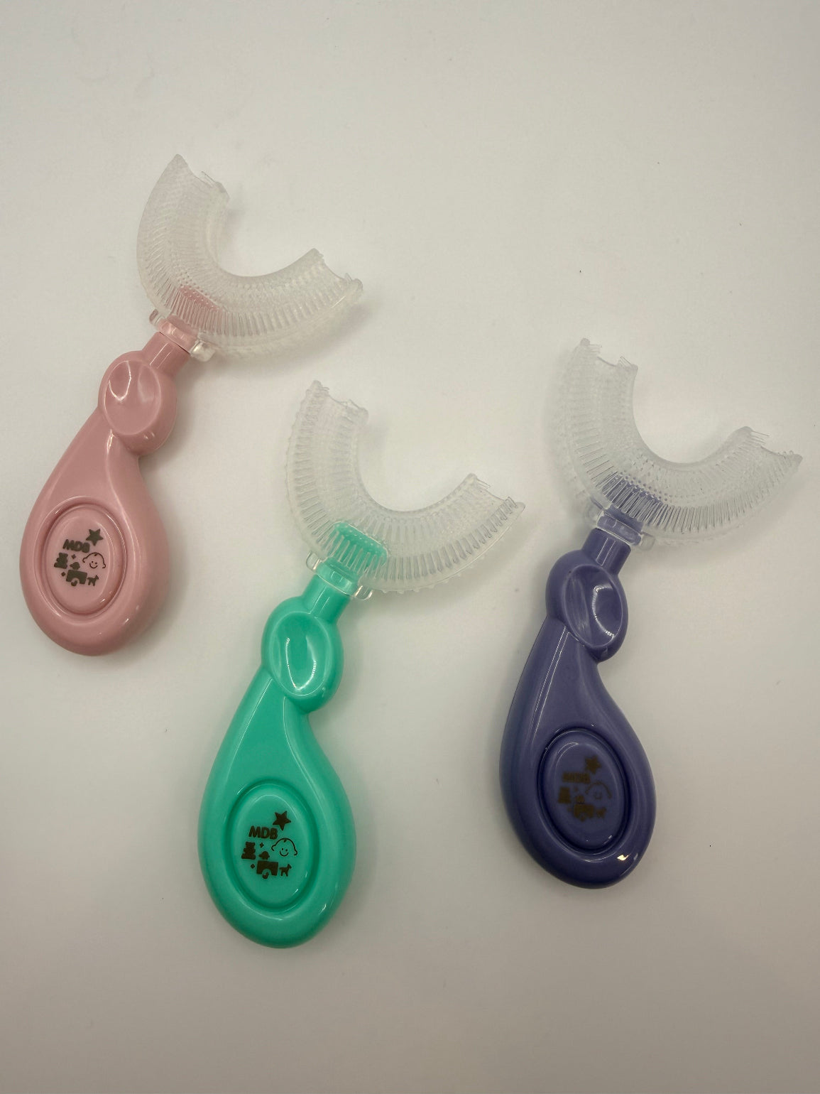 3 U-shaped sensory toothbrushes. Green, purple and pink on a white background.