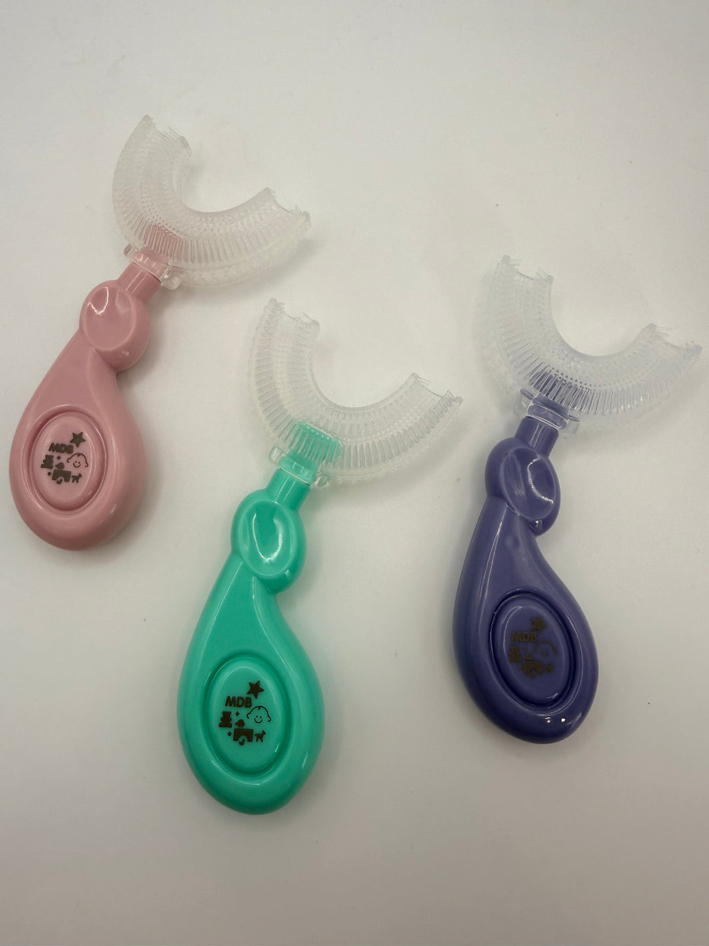 3 U-shaped sensory toothbrushes. Green, purple and pink on a white background.