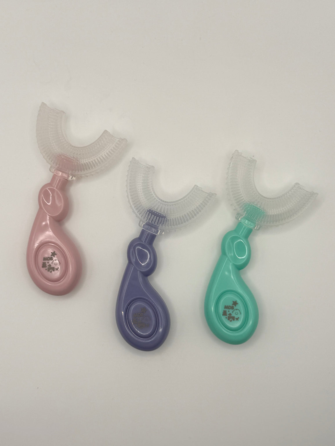3 U-shaped sensory toothbrushes. Green, purple and pink on a white background.