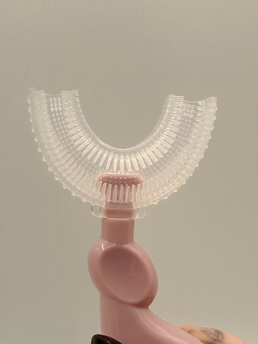 Pink U-shaped sensory toothbrush on a white background.