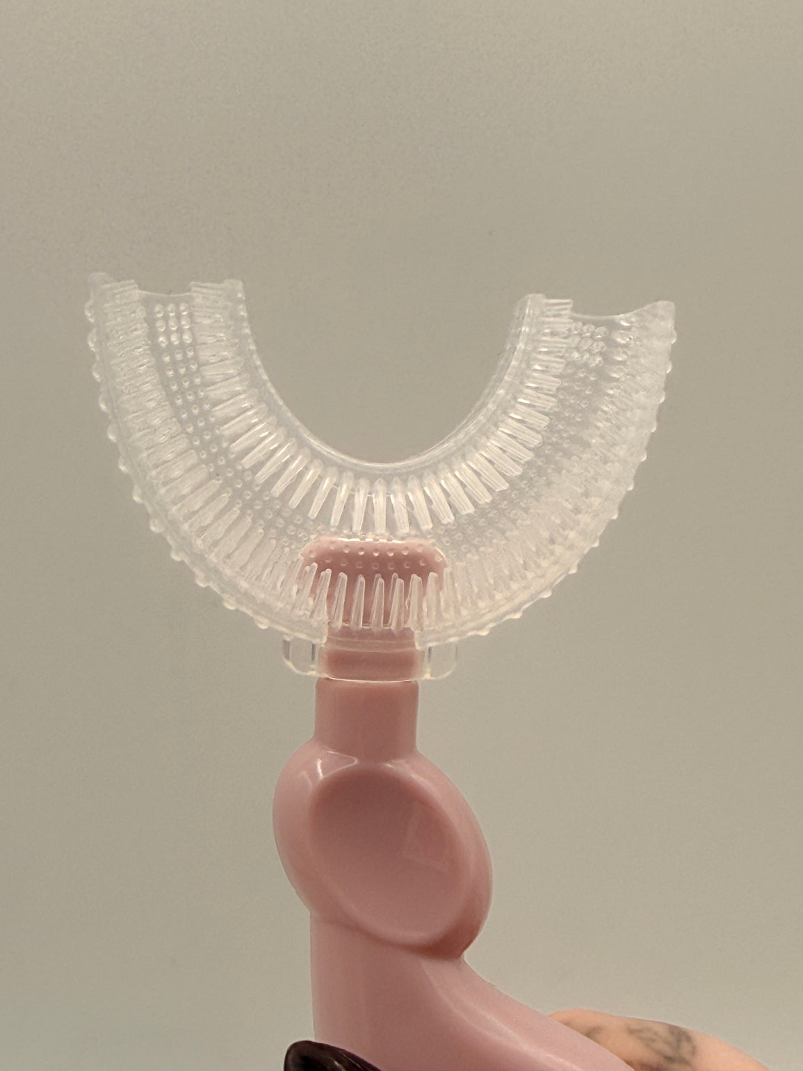 Pink U-shaped sensory toothbrush on a white background.