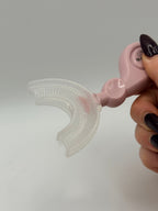 Pink U-shaped sensory toothbrush on a white background.